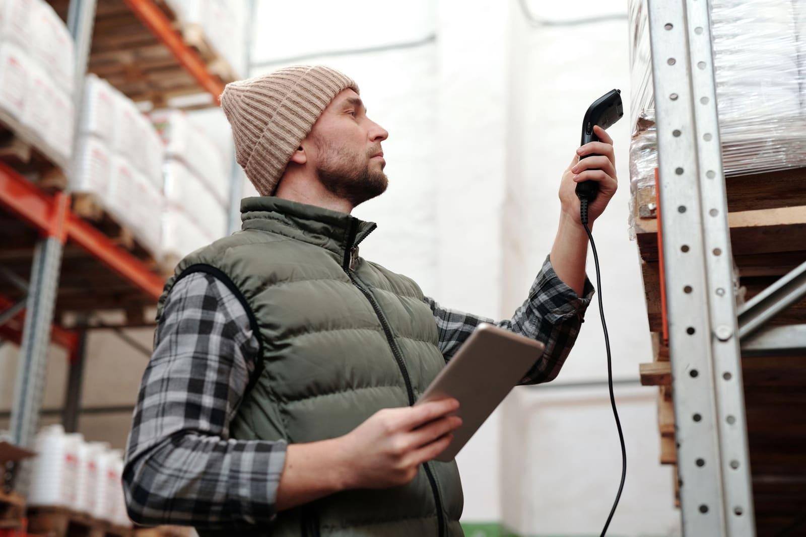 A warehouse operative using a handheld scanner and tablet to record stock.